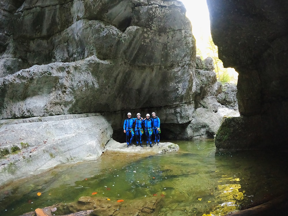 Group of family or friends canyoning in the stunning Almbachklamm, sunlight shining through the gorge, sparkling water from the sun. Impressive towering rock walls.
