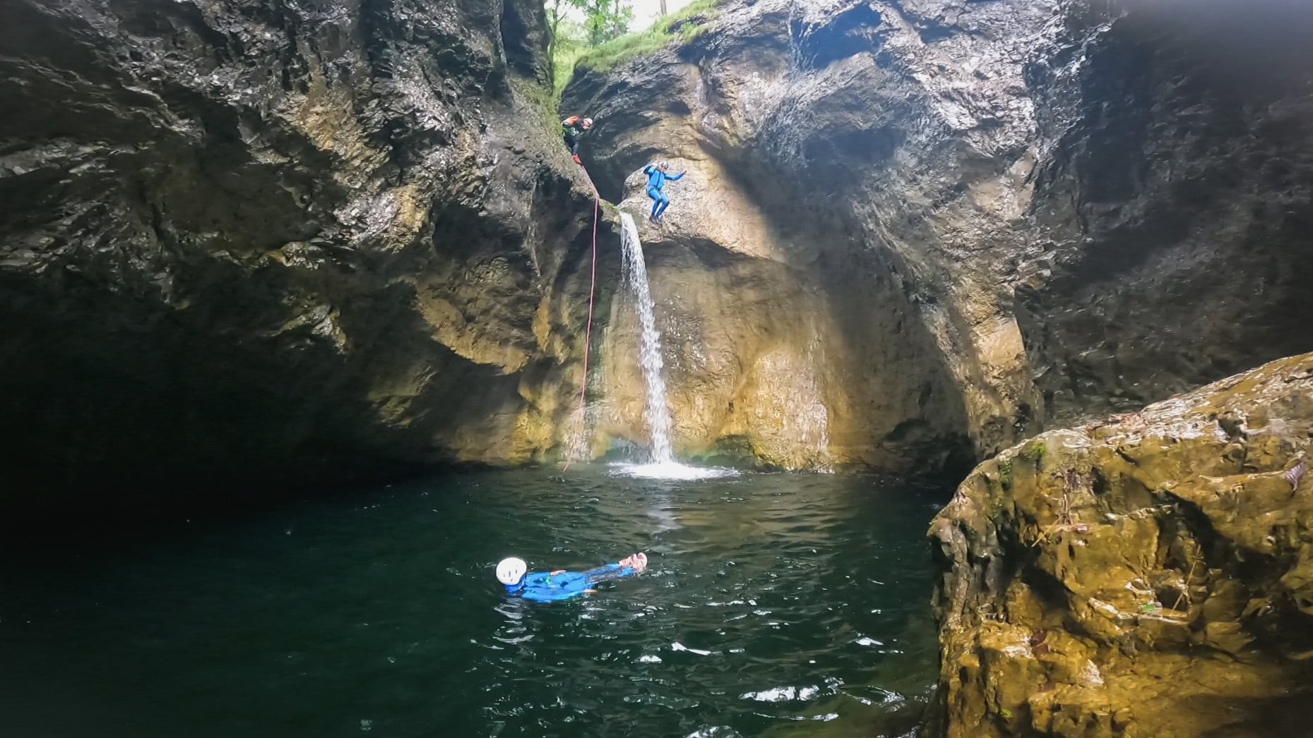 Canyoning Strubklamm - waterfall jumps for adrenaline fans in Salzburgerland Best Canyoning Austria: Customer swims in the emerald green water pool of the Strubklamm gorge after a jump from the waterfall - canyoning tour with guide Paul Murray in Salzburgerland.
