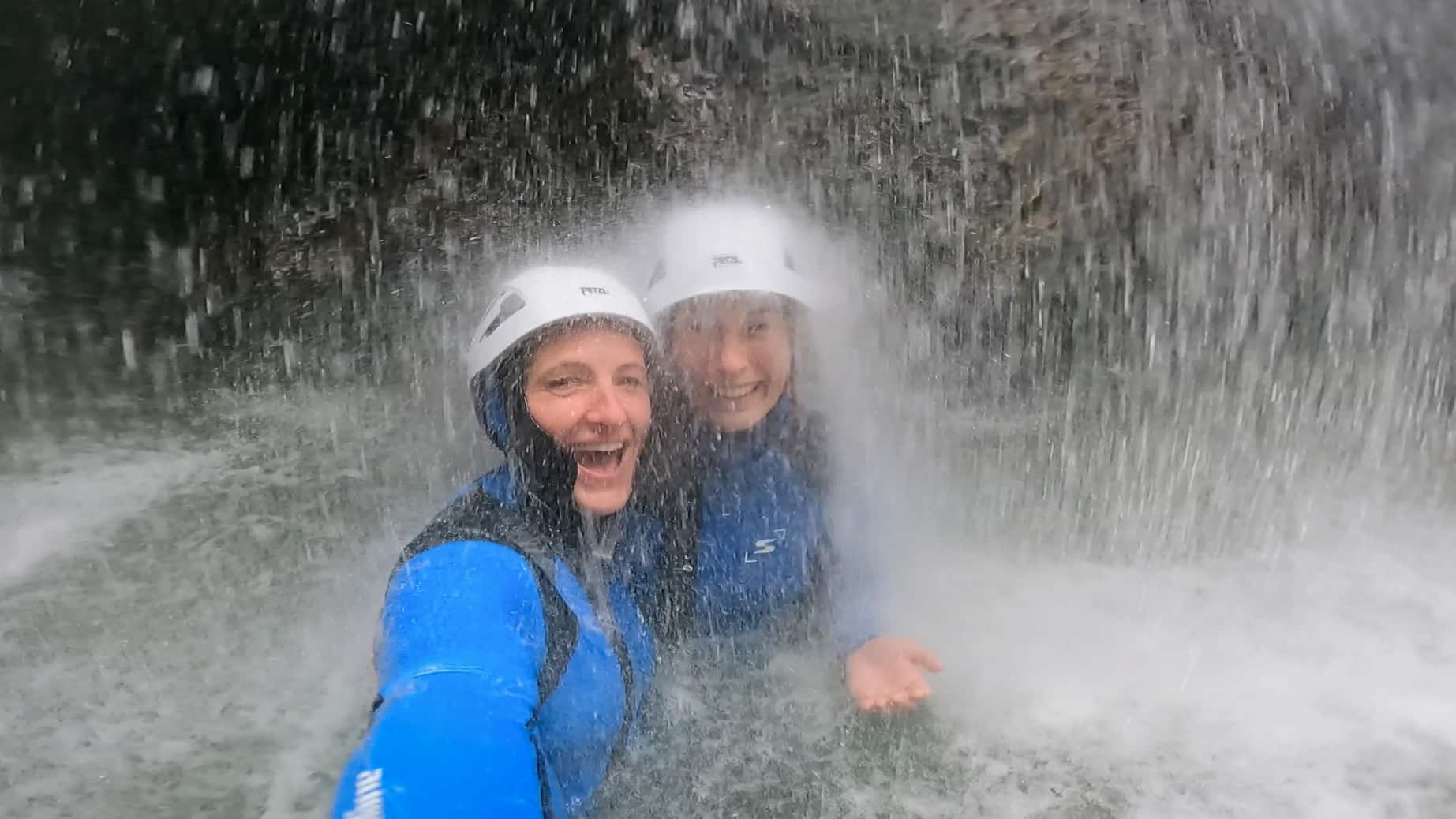Canyoning Strubklamm - adventure under the waterfall near Salzburg Two canyoning guests under a thundering waterfall in the Strubklamm gorge in Faistenau - guided canyoning tour in Salzburgerland with Paul Murray.