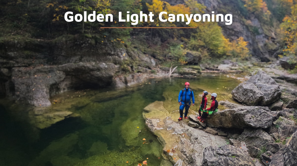 Eine geführte Canyoning-Gruppe in Neoprenanzügen neben einem klaren Wasserbecken, umgeben von Herbstlaub, in der Almbachklamm bei Salzburg im September
